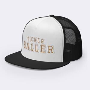 May include: White and black trucker hat with a gold embroidered design that says "Pickle Baller".