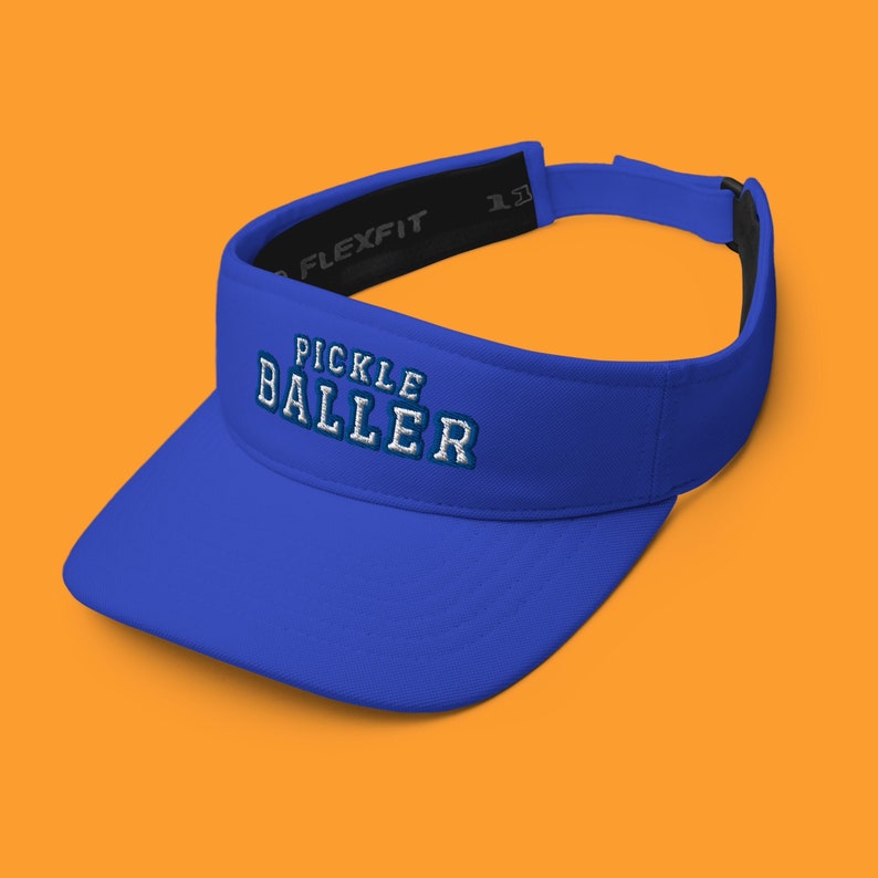 K&ouml;nnte beinhalten: Ein k&ouml;nigsblauer Visier mit einem verstellbaren schwarzen Band und dem gestickten Text "PICKLE BALLER" in Wei&szlig; mit blauer Umrandung.