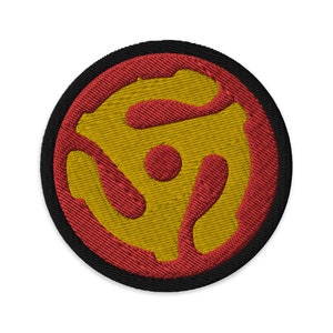 May include: A red and gold embroidered patch with a stylized record design. The patch is circular and has a black border.