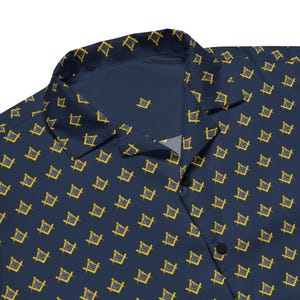 May include: Navy blue button-down shirt with a repeating yellow and gray square and compass pattern. The shirt has a classic collar and black buttons. The fabric has a slight sheen.