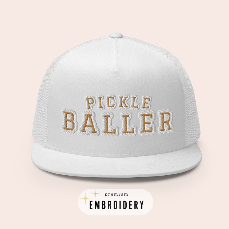 May include: White trucker hat with a gold embroidered design that says "Pickle Baller". The hat has a mesh back and a curved brim. The text "premium embroidery" is also visible in the image.