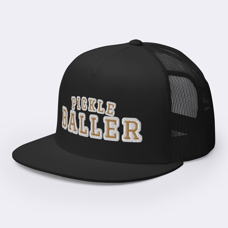 May include: Black trucker hat with a white mesh back. The front of the hat has the words "Pickle Baller" embroidered in white and gold.