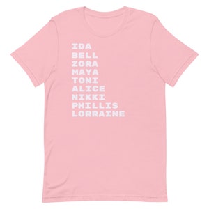 K&ouml;nnte beinhalten: Rosafarbenes T-Shirt mit wei&szlig;em Text, der "Ida Bell Zora Maya Toni Alice Nikki Phillis Lorraine" lautet.