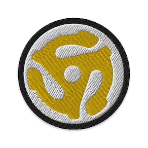 May include: A round, white and gold embroidered patch with a stylised record design. The patch has a black border.