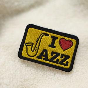 May include: Yellow embroidered patch with black stitching and a red heart. The patch says "I love Jazz" with a saxophone graphic.