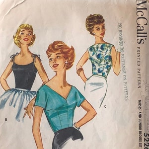 May include: Vintage McCall's printed pattern featuring illustrations of three different blouse designs. The blouses are in black, teal, and a blue and white floral print. The pattern includes the text "MISSES' AND JUNIOR BLOUSE SET".