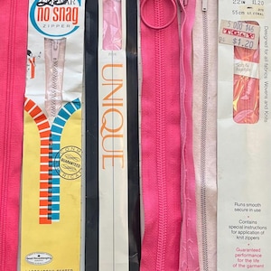 May include: A selection of vintage pink zippers, including a "No Snag" zipper and a "Talon Lightweight Knit" zipper, with packaging. The image features text such as "Laboratory Tested" and "Guaranteed performance for the life of the garment". The "Talon" zipper is 55cm long.