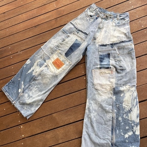 Op de afbeelding: Lichtblauwe denim jeans met meerdere patches en distressed details. De jeans zijn gebleekt en hebben een vervaagde look.