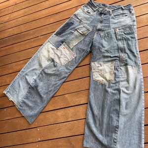 Könnte beinhalten: Eine blaue Jeans aus Denim mit mehreren Patches in verschiedenen Blautönen. Die Jeans hat eine weite Beinweite und einen niedrigen Bund.