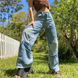 May include: A pair of blue denim jeans with multiple patches sewn on. The jeans are wide-legged and have a high waist.