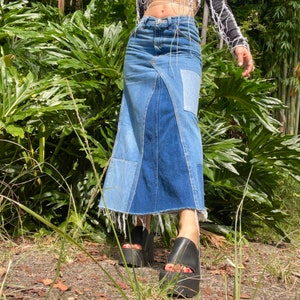 May include: A long denim skirt made from different shades of blue denim with a frayed hem. The skirt is patchwork style and has a straight silhouette.