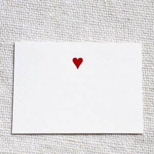May include: A white card with a red heart in the center.