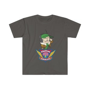 May include: Dark grey t-shirt with a cartoon character wearing a green cap, aviator jacket, and headset. The shirt displays a colourful emblem with the words "Cranium Command" and a brain graphic with wings.