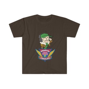 May include: A brown t-shirt with a cartoon character wearing a green cap and headset. The design includes the words "Cranium Command" and a brain graphic with wings.