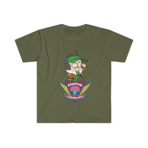 May include: An olive green t-shirt with a cartoon character wearing a green cap and headset. The design includes the words "Cranium Command" and a brain graphic with wings. The text "Cranium Command" is displayed below the brain graphic.