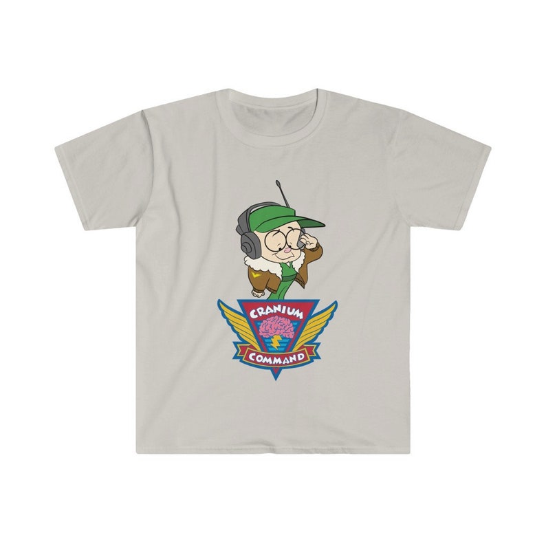 May include: A light grey t-shirt with a cartoon character wearing a green hat and headset. The character is above a colorful emblem that reads "Cranium Command" with a brain graphic. The shirt is made of a soft material.