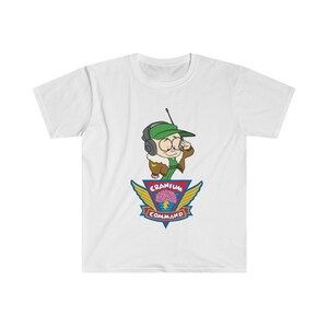 May include: White t-shirt with a cartoon character wearing a green cap and headset. The design includes the text "Cranium Command" and a brain graphic with wings. The shirt is made of a soft material. A fun, casual tee.
