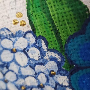 May include: Close-up of a painting featuring blue and white hydrangea flowers with gold accents and a large green leaf. The artwork has a textured, impasto style, with a white background.