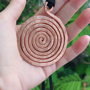 Peut inclure: Un collier avec un pendentif en spirale de cuivre martelé. Le pendentif est attaché à un cordon noir.
