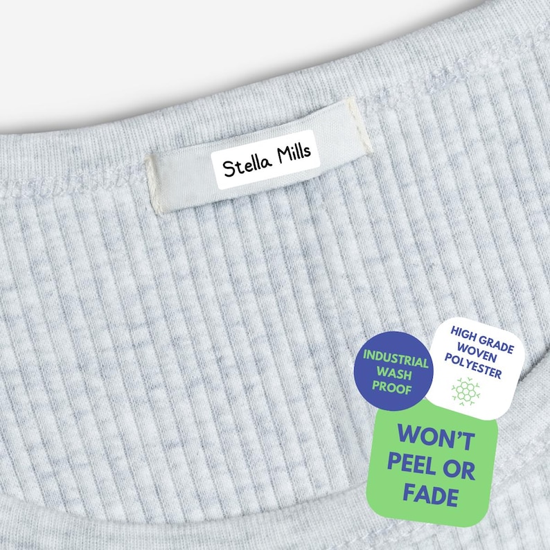 May include: A light gray ribbed fabric garment featuring a white rectangular clothing label with the black text Stella Mills. Three circular and square stickers are attached, displaying the text Industrial Wash Proof, High Grade Woven Polyester, and Won't Peel Or Fade.