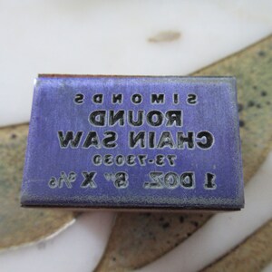 May include: A purple box with white text that reads "1 DOZ. 8" x 3/16" 73-7320 CHAIN SAW ROUND SIMONS".