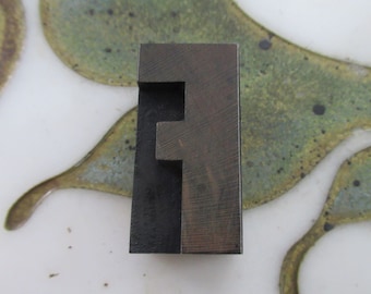 Può includere: Un blocco di stampa tipografica in metallo vintage della lettera F. Il blocco è in metallo scuro e ha una superficie usurata e testurizzata.
