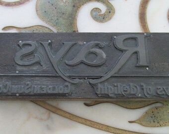 Puede incluir: Un bloque de impresión vintage con la palabra "Rays" en una fuente decorativa. El texto "high piled to every Golden Sun" también es visible en el bloque.