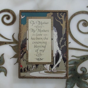Könnte beinhalten: Ein gerahmter Kunstdruck mit dem Text "To Mother, My Mother's love has been the crowning blessing of my life." Das Kunstwerk zeigt eine Landschaft mit einem Brunnen und Bäumen, gerahmt in einem goldfarbenen Rahmen.