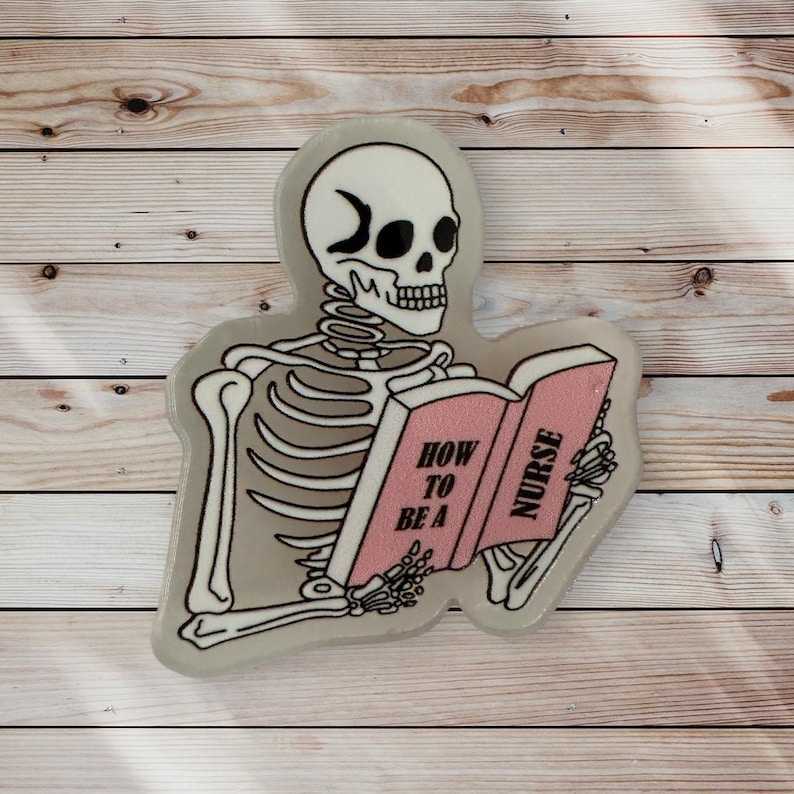 May include: A white skeleton with a crescent moon on its forehead is reading a pink book titled "How to be a Nurse".