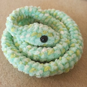 May include: A crocheted green and white snake toy with a black button eye.