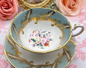 May include: A vintage teacup and saucer set with a delicate floral design and gold trim. The teacup and saucer are a pale blue color with a white interior.
