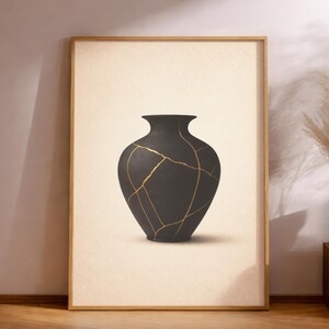 May include: A framed print featuring a black vase with gold-colored lines, showcasing the Japanese art of Kintsugi. The vase is centered on a cream-colored background, with a wooden frame. The artwork is displayed on a wooden floor.