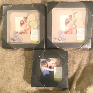 May include: Three Studio Decor picture frames. Two frames contain a photo of a pregnant couple, with the text "Excited to meet my nephew!" and "Congrats! Can't wait to babysit!" written on them. The third frame has a photo of a dog and a cat.
