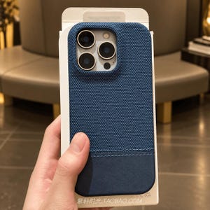 Könnte beinhalten: Eine blaue Smartphone-Hülle mit einem strukturierten Gewebe im oberen Bereich und einem glatten, einfarbigen unteren Teil. Die Hülle hat einen quadratischen Kameraausschnitt mit drei Linsen und den Text 紫轩时光.TAOBAO.COM am unteren Rand.