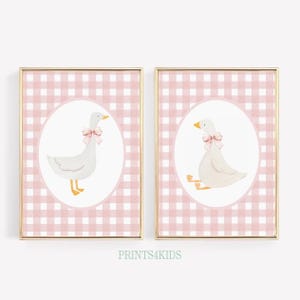 Pode incluir: Duas impressões de arte imprimíveis com um ganso branco com um laço rosa em um fundo xadrez rosa e branco. As impressões estão em molduras douradas.