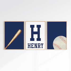 K&ouml;nnte beinhalten: Drei gerahmte Drucke mit einem marineblauen Hintergrund. Der linke Druck zeigt einen h&ouml;lzernen Baseballschl&auml;ger. Der mittlere Druck zeigt einen gro&szlig;en marineblauen Buchstaben H und den Namen HENRY in marineblauem Text. Der rechte Druck zeigt einen wei&szlig;en Baseball mit roten N&auml;hten.