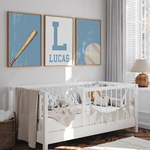 K&ouml;nnte beinhalten: Drei blaue und wei&szlig;e gerahmte Drucke mit Baseball-Motiven. Die Drucke zeigen einen Baseballschl&auml;ger, den Buchstaben L und einen Baseball. Der mittlere Druck tr&auml;gt den Namen Lucas unter dem Buchstaben L.