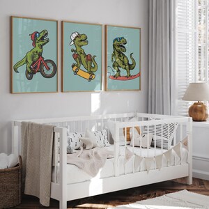 Puede incluir: Tres ilustraciones enmarcadas de dinosaurios verdes sobre un fondo azul claro. Los dinosaurios van en bicicleta, patineta y surf. Los marcos son de madera con un acabado marr&oacute;n claro.