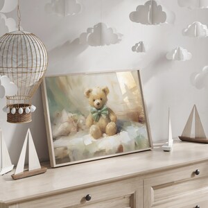 May include: A framed print of a teddy bear with a green bow tie. The artwork is displayed on a light wood dresser, with decorative sailboats and a hot air balloon nearby. White paper clouds hang from the ceiling.