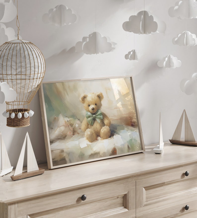 May include: A framed print of a teddy bear with a green bow tie. The artwork is displayed on a light wood dresser, with decorative sailboats and a hot air balloon nearby. White paper clouds hang from the ceiling.