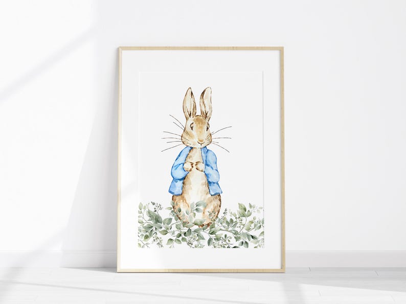 May include: Watercolor illustration of a rabbit wearing a blue jacket, set against a white background. The framed artwork features the rabbit standing amidst green foliage. The artwork is in a light wooden frame.