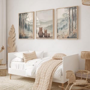 May include: Three framed watercolour prints showing forest scenes and a bear family. The prints are above a white bed with beige bedding and pillows. A wooden rocking horse and a woven basket are also visible.