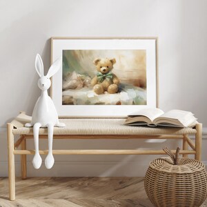 May include: A framed print of a teddy bear with a green bow tie sits on a bench. A white ceramic rabbit and an open book are also on the bench. A woven basket with an apple-shaped lid is on the floor.