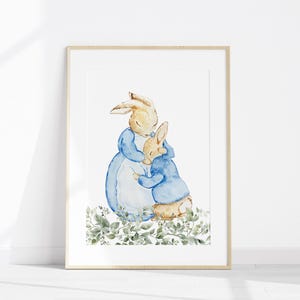 May include: Watercolor illustration of two rabbits, one larger and one smaller, embracing. The rabbits are depicted in soft, muted colors with the larger rabbit wearing a blue dress and the smaller rabbit wearing a blue jacket. The artwork is framed.