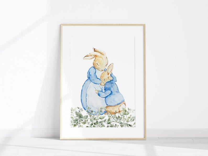May include: Watercolor illustration of two rabbits, one larger and one smaller, embracing. The rabbits are depicted in soft, muted colors with the larger rabbit wearing a blue dress and the smaller rabbit wearing a blue jacket. The artwork is framed.