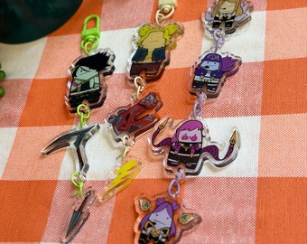 May include: A set of six clear acrylic keychains featuring cartoon characters from the video game League of Legends. The characters are dressed in colorful outfits and have different expressions. The keychains are attached to silver chains and have a clear acrylic charm with a cartoon character on it.