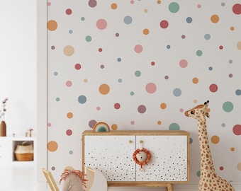 May include: A white wall with colorful polka dots in various sizes. A wooden cabinet with black and white polka dots is in the foreground. A stuffed giraffe and a doll in a stroller are also in the foreground.