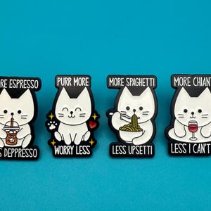 Könnte beinhalten: Vier schwarz-weiße Katzen-Anstecknadeln mit humorvollem Text. Die Anstecknadeln zeigen eine weiße Katze mit schwarzen Umrissen, jede mit einem anderen Thema: Espresso, Schnurren, Spaghetti und Chianti. Der Text lautet "More Espresso, Less Depresso", "Purr More, Worry Less".