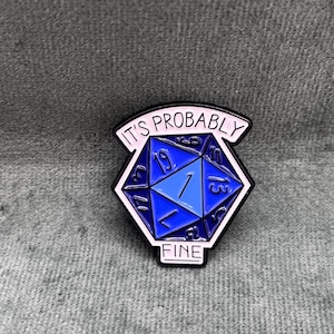 Könnte beinhalten: Eine blaue und weiße Emaille-Anstecknadel mit einem blauen 20-seitigen Würfel und dem Text "It's Probably Fine".