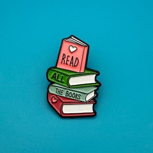 Könnte beinhalten: Ein Stapel von drei Büchern mit den Worten "READ", "ALL" und "THE BOOKS" auf den Buchrücken. Das oberste Buch ist rosa mit einem weißen Herzen, das mittlere Buch ist grün und das untere Buch ist rot. Der Hintergrund ist einfarbig türkis.